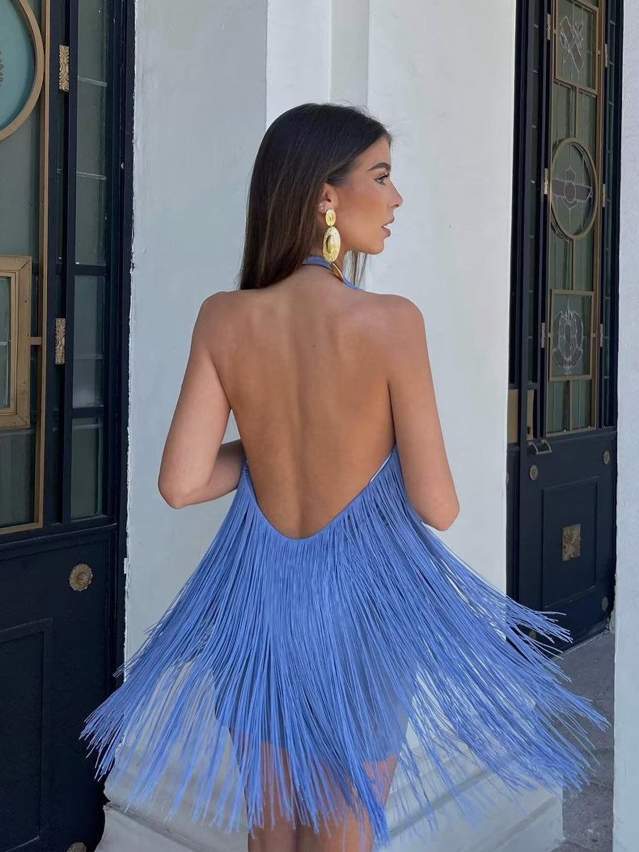 Woman wearing a blue fringe dress standing in front of a white wall.